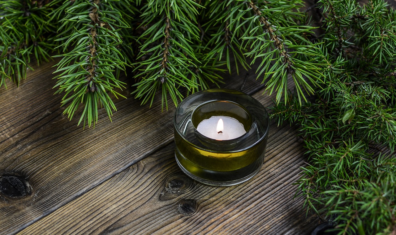 Photo of the new Christmas candle by Lavish Scents. Candle on a wooden floor next to a Christmas tree.